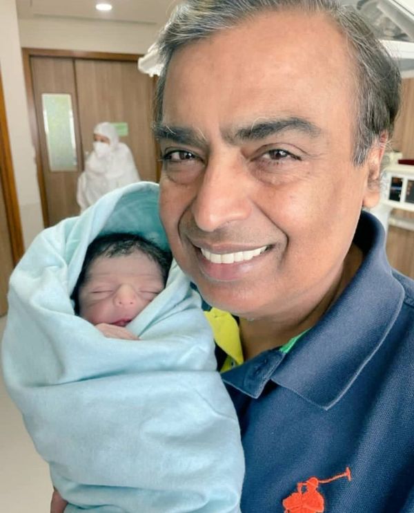 Mukesh Ambani holding his newborn grandson in his lap