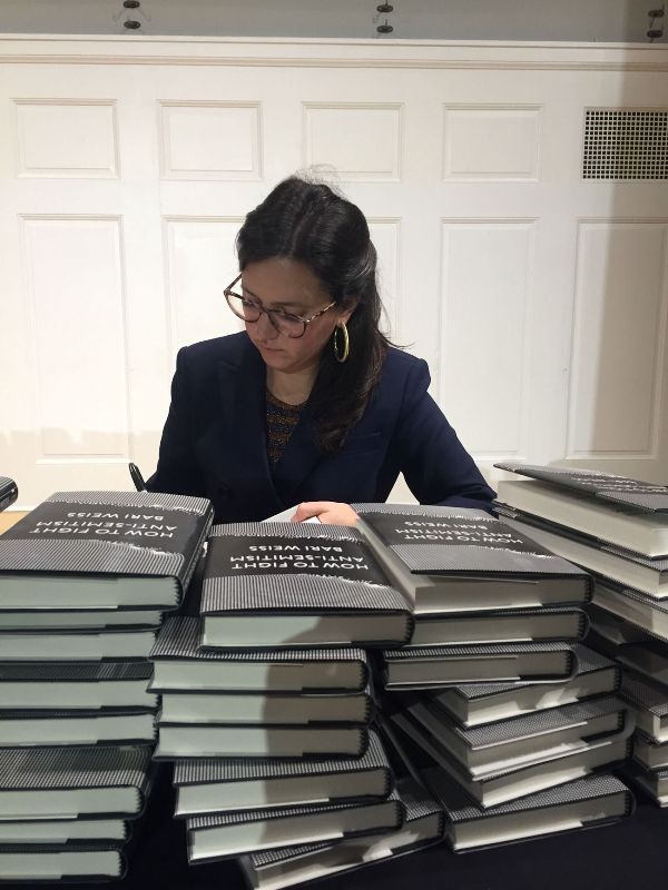 Bari Weiss with a pile of her book, How to Fight Anti-Semitism