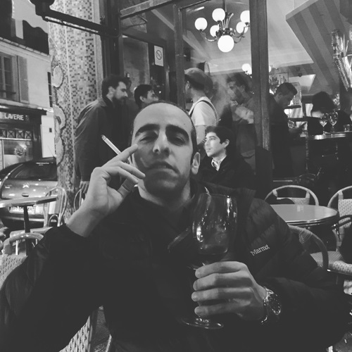 Dan Ahdoot enjoying wine and a cigarette at a restaurant