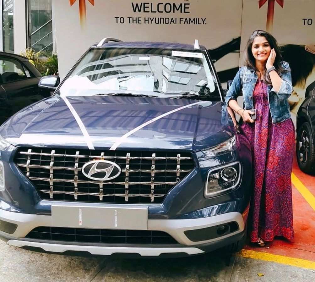 Divya Uruduga posing next to her car