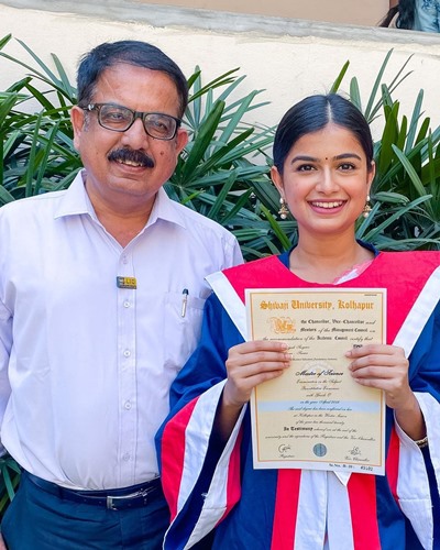 Hemal Ingle holding her master's degree with her father
