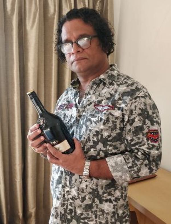 Hareesh Peradi holding a bottle of alcohol