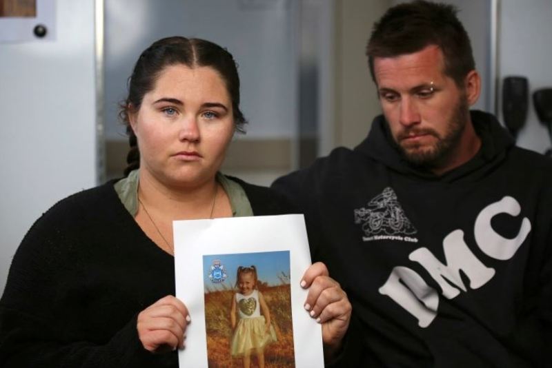 Cleo Smith’s mother, Ellie Smith, with her partner, Jake Gliddon, holds up a photo of Cleo while addressing the case from a police truck at Blowholes campsite, outside Carnarvon, Australia, October 19, 2021