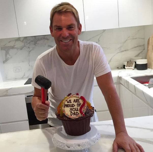 Shane Warne posing with a cake