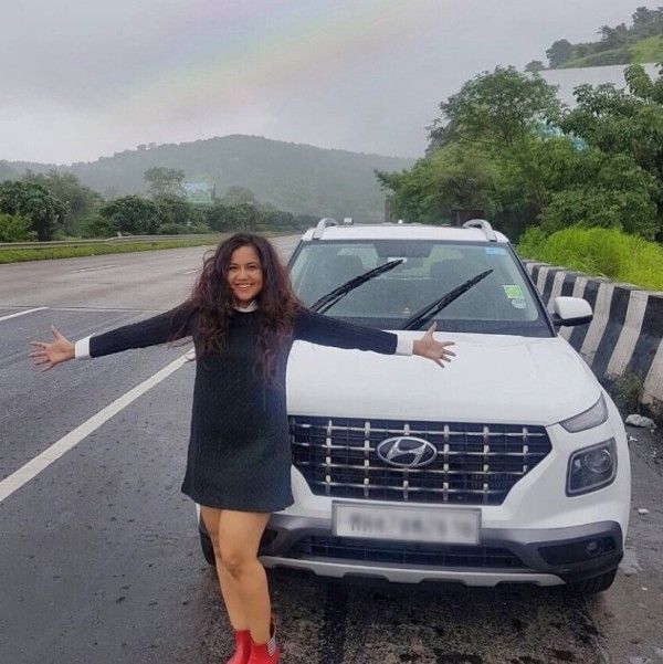 Roopal Tyagi standing in front of her car