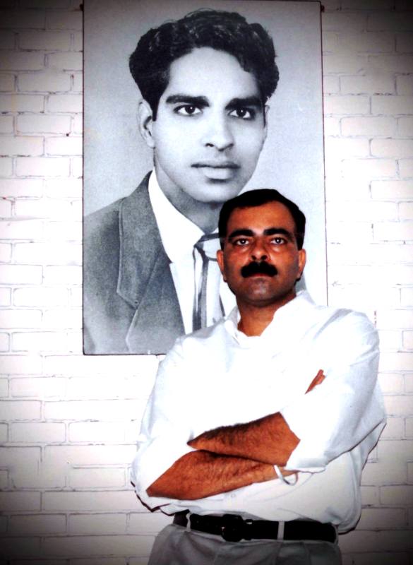 Sanjay Popli posing infront of his father's portrait