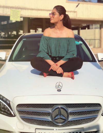 Akanksha Puri sitting on her car