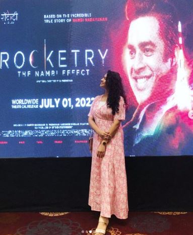 Misha Ghoshal standing in front of the poster of the film Rocketry: The Nambi Effect