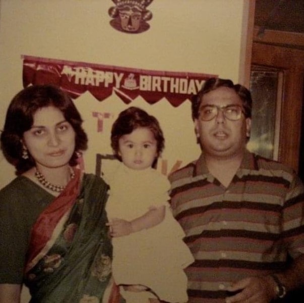 Radhika Gupta's parents holding her as a child