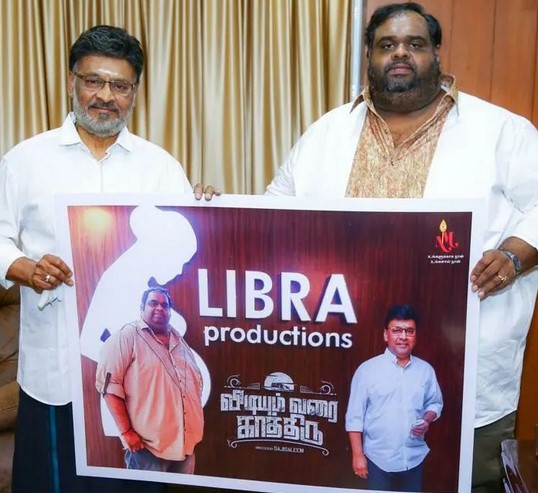 Ravindar Chandrasekaran with the poster of his film production banner