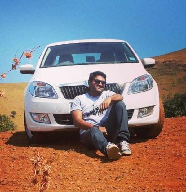 Rishab Shetty sitting in front of his car, Skoda Fabia