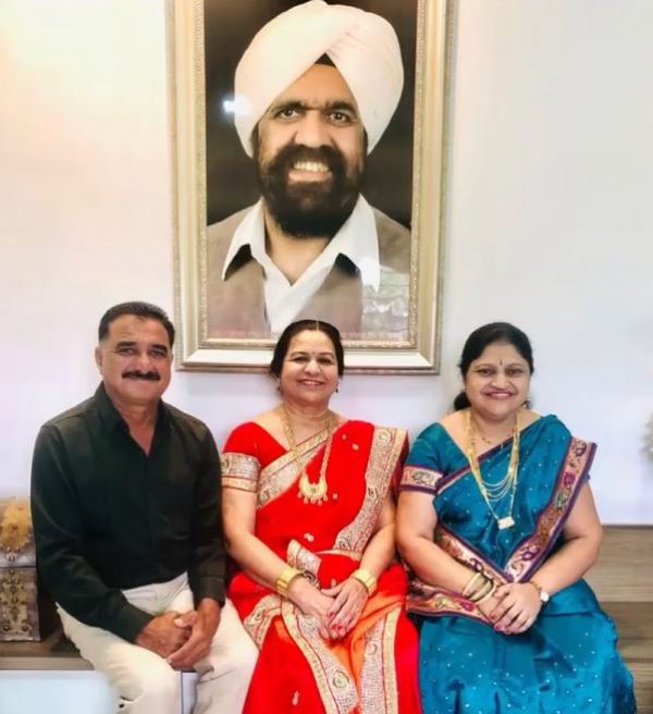 Trishul Marathe's father (left), mother (centre), and aunt (right), posing in front of Guru Sant Rajinder Singh Ji Maharaj's portrait