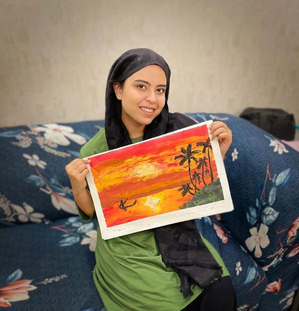 Saba Ibrahim holding a painting made by her
