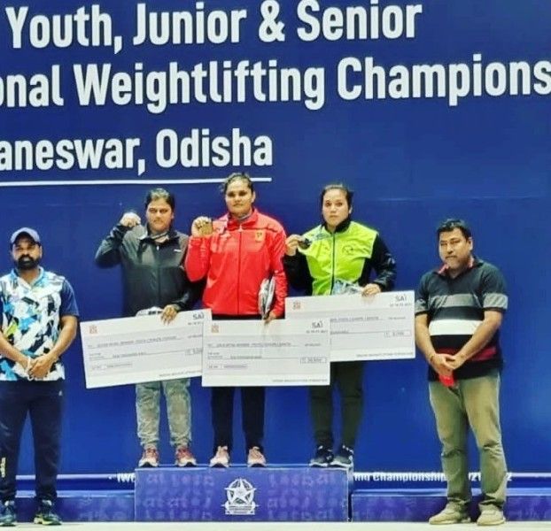 Usha Kumara on podium after winning gold in IWLF Youth Junior And Senior National Weightlifting Championships in 2022