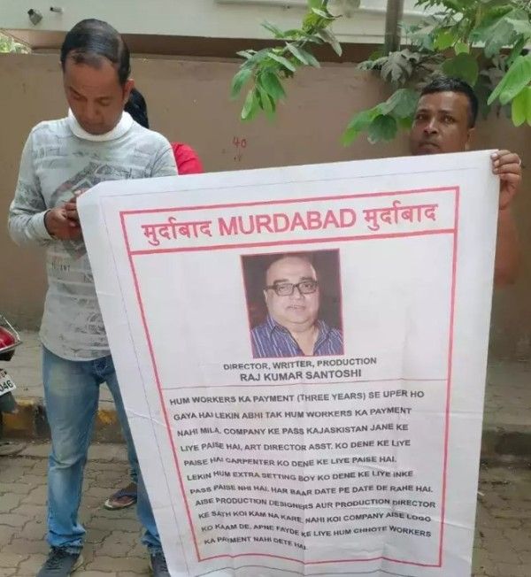 A fim crew member protesting against Rajkumar Santoshi with a poster