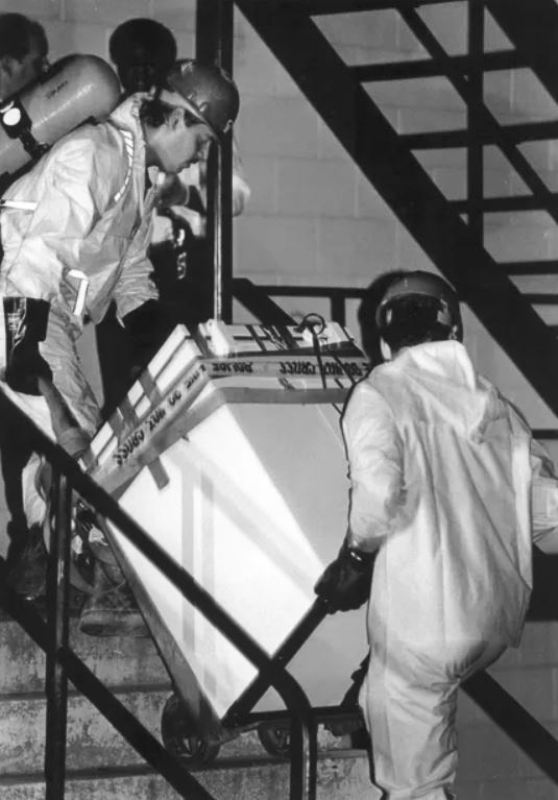 Officials wearing hazardous material suits to carry Jeffrey Dahmer's freezer down steps at his apartment building in 1991
