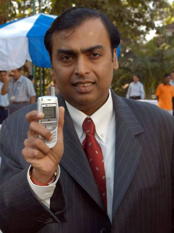 27 December 2002: Mukesh Ambani displaying a new handset at the launch of a nationwide mobile telephony service in Mumbai