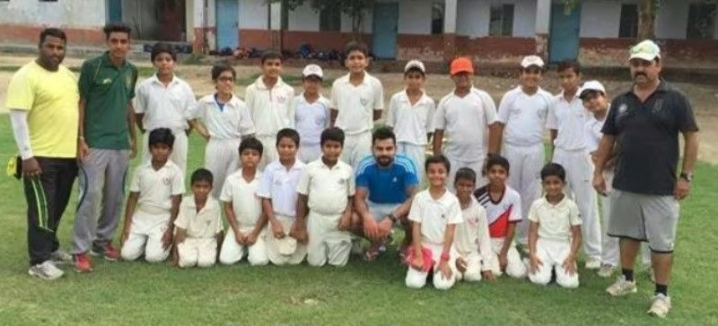 A photograph of Rajkumar Sharma and Virat Kohli with the students of the West Delhi Cricket Academy