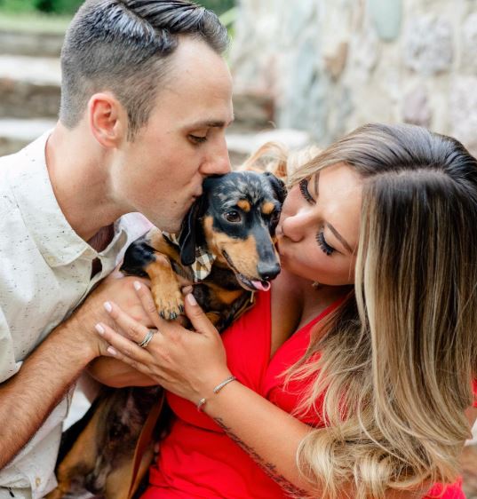 Matt Moeller and Alaina Scott kissing their pet dog