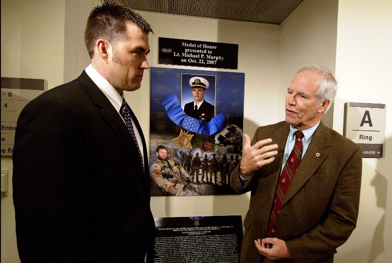 Michael P. Murphy's father with Navy SEAL Marcus Luttrell standing next to Michael's photo installed at the Hall of Heroes in the Pentagon