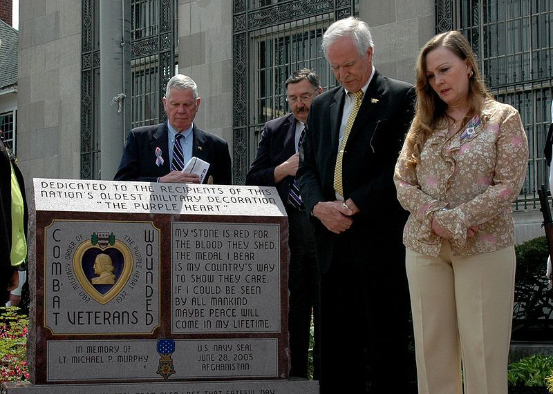 Murphy's parents standing next to a monument installed by the US government at the post office in his hometown