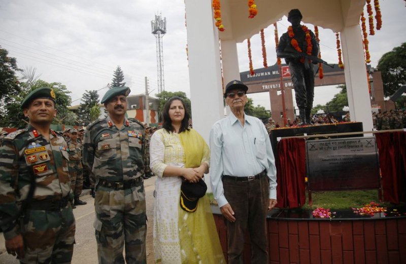 A photo of Triveni Singh's family members and officers of the Indian Army standing next to the statue of Triveni Singh at the Sunjuwan Military Station