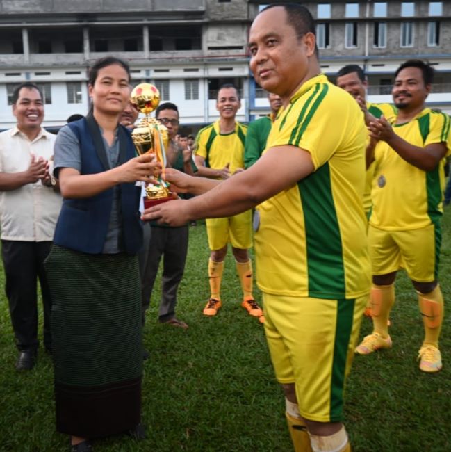Animesh Debbarma receiving a trophy for winning a football match