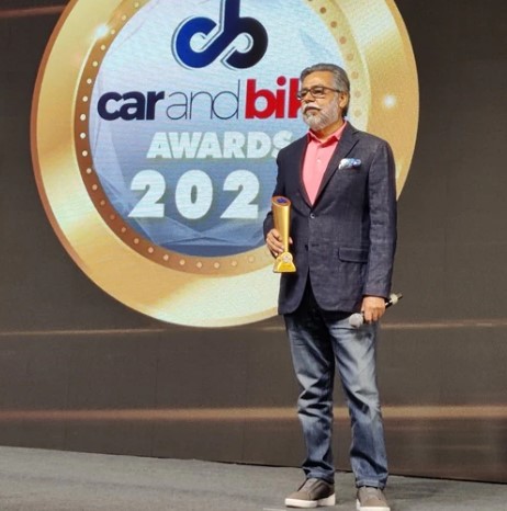 Pawan Munjal posing with the Visionary Award by Car and Bill in 2021
