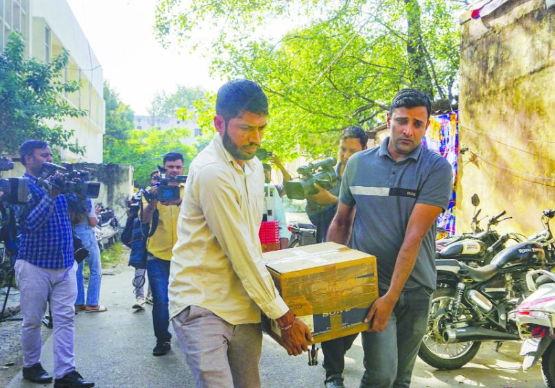 Delhi police staff carrying the material seized during the raids at NewsClick office in Delhi