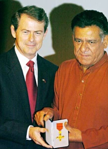Om Puri (right) receiving the honour of the Most Excellent Order of the British Empire (OBE) in 2004