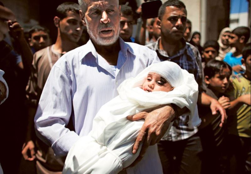Widad Asfoura's father carrying the dead body of Ali Deif, the son of Hamas military commander Mohammed Deif while taking it to the mosque during his funeral at the Jabalia refugee camp in the northern Gaza Strip