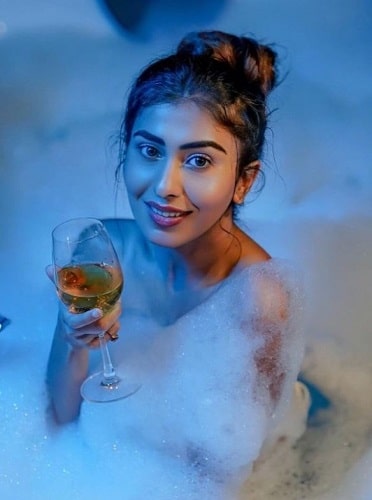 A picture of Ruma Sharma holding a glass of wine