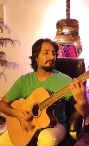 A picture of Ashim Kemson playing a guitar