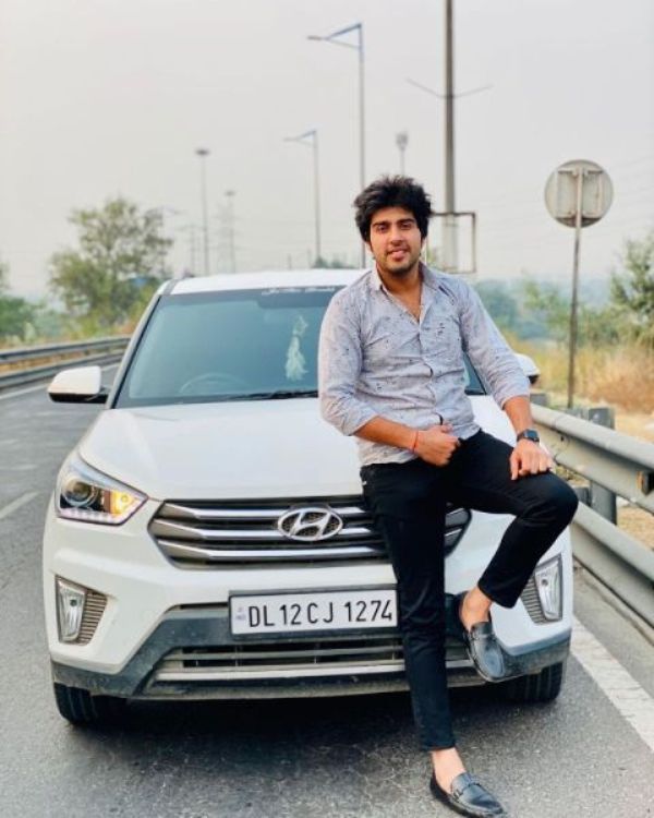 Akash Sansanwal posing in front of his car