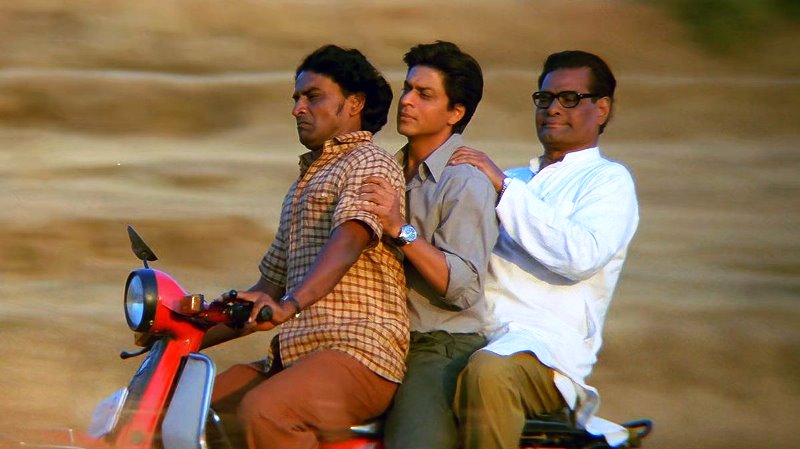 Daya Shankar Pandey, Shah Rukh Khan, and Rajesh Vivek riding a moped during a scene in the film Swades (2004)