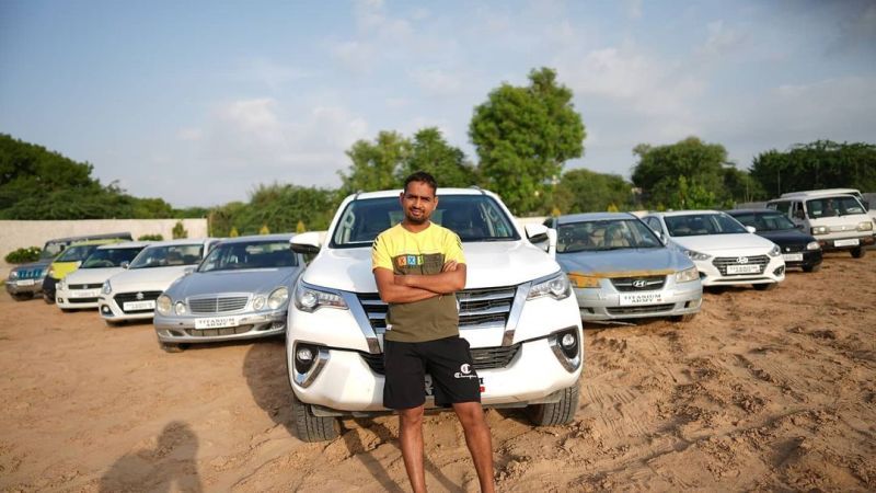 Dilraj Singh posing with entire collection of cars