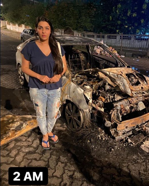 Yamini standing with her burnt car